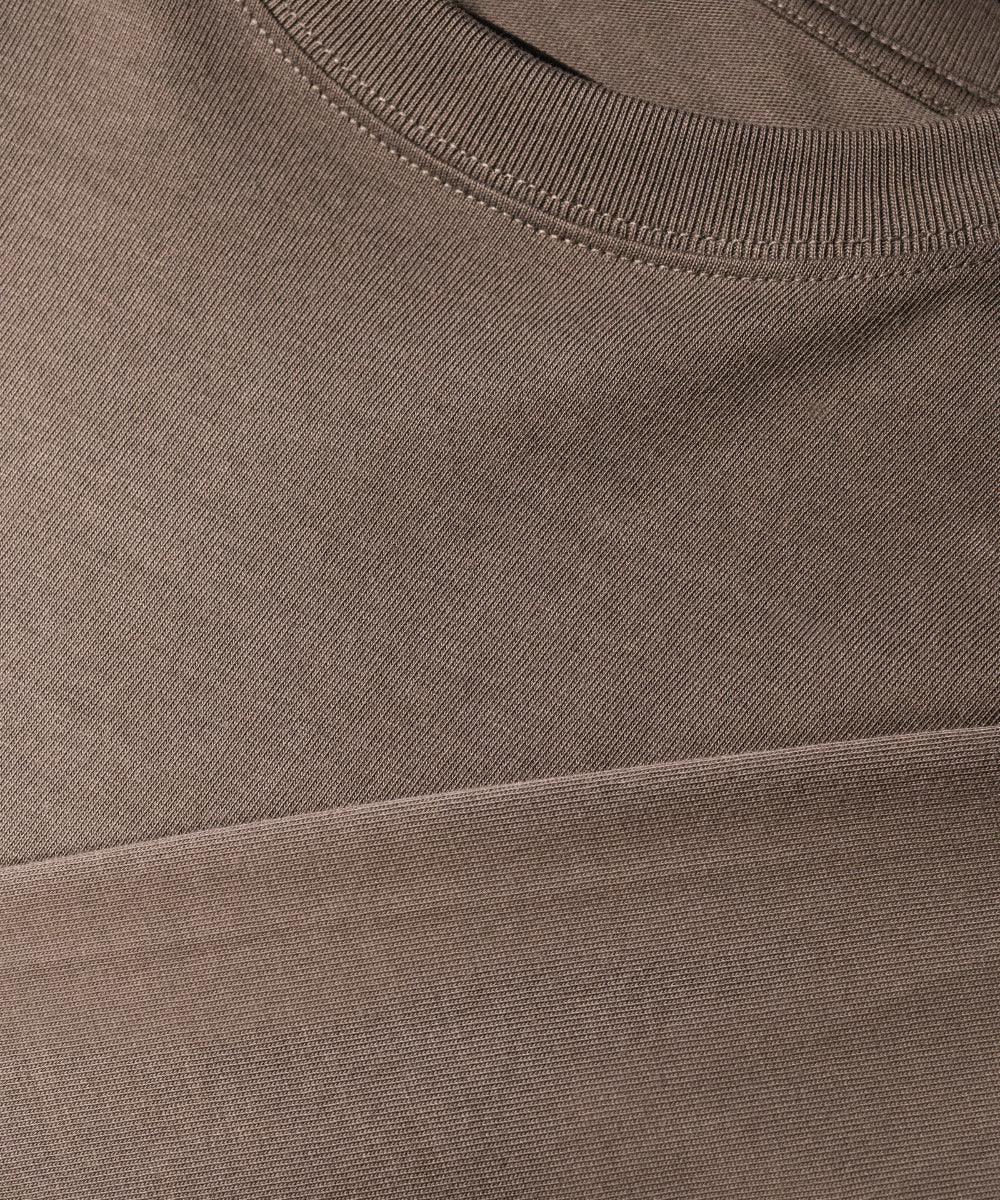 Close-up of a ribbed crew neck t-shirt in a muted taupe-brown color, showing the fine knit texture and stitching.