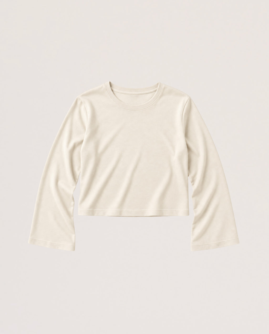 A long-sleeve cropped knit top in a warm off-white or cream color, displayed flat against a solid, light beige background.