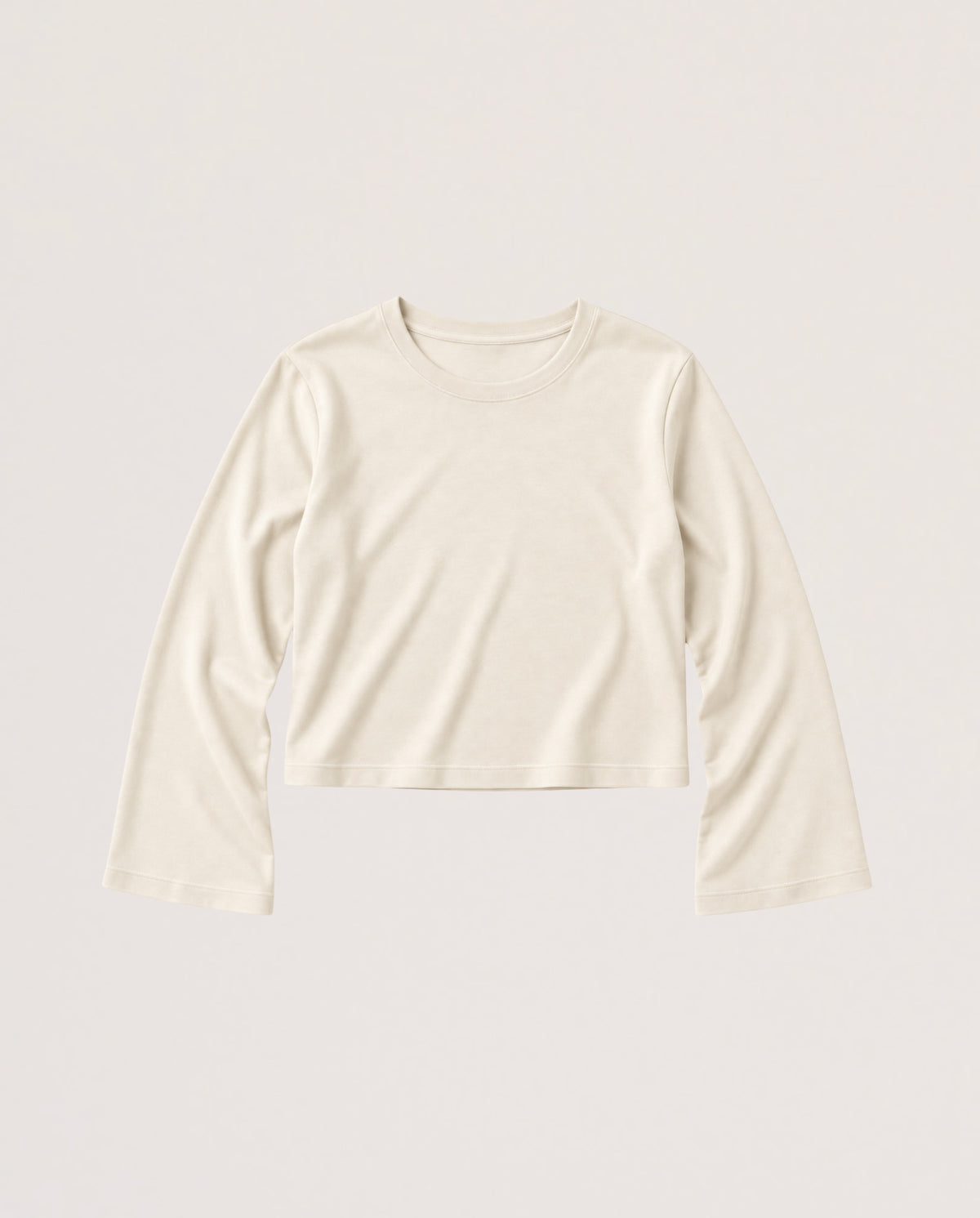 A long-sleeve cropped knit top in a warm off-white or cream color, displayed flat against a solid, light beige background.
