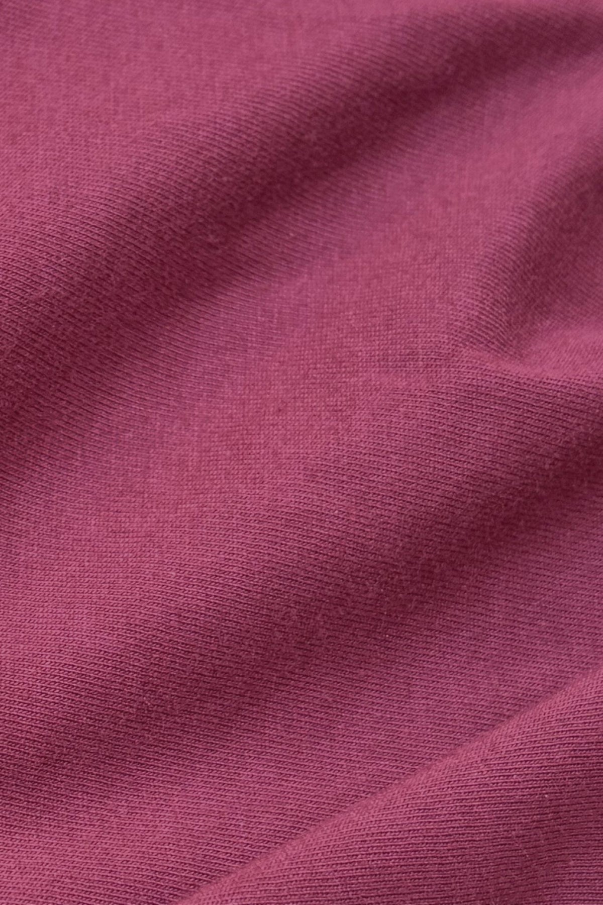 A close-up of draped fabric in a dusty rose or mauve pink color, showing the fine knit texture and soft folds.
