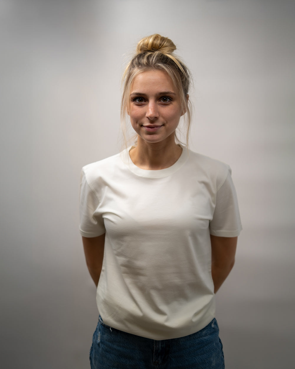 Person wearing a plain white t-shirt against a gray background