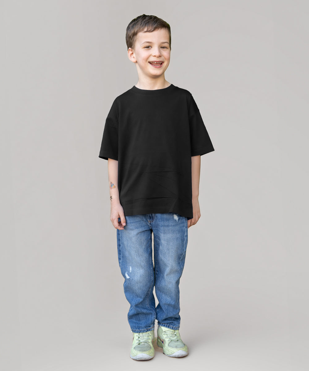 Child wearing a black t-shirt and blue jeans on a gray background