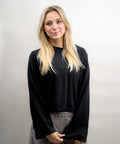 Person wearing a black long-sleeve top against a plain background
